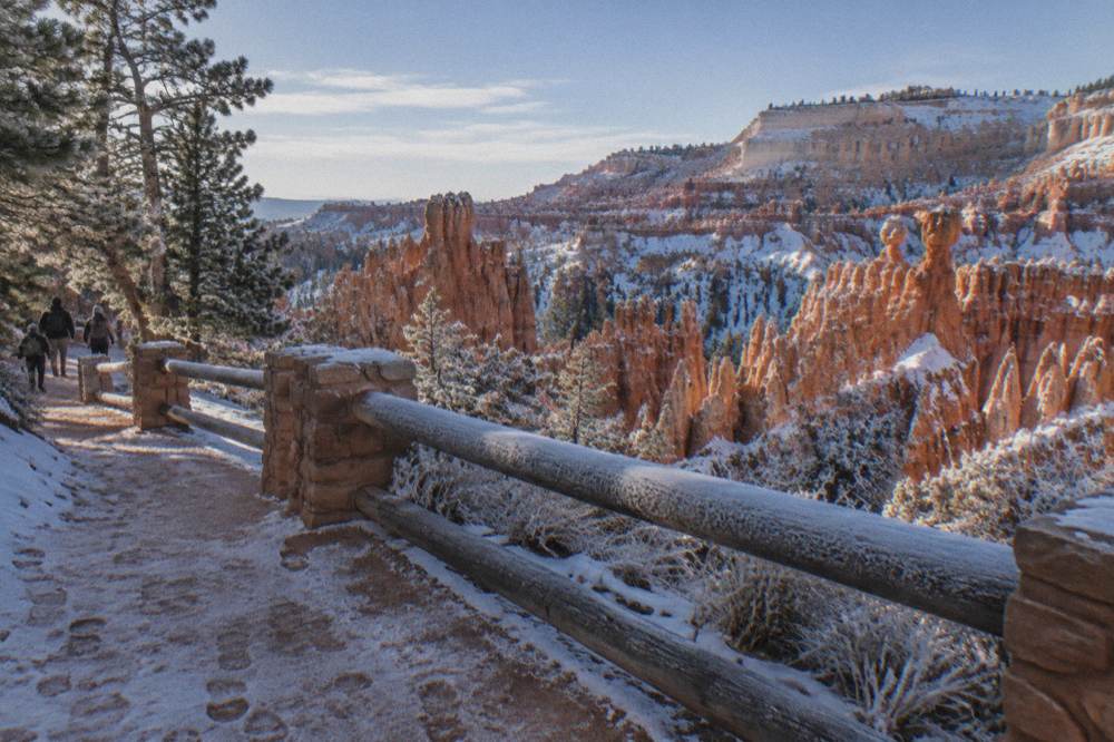 Snow dusted red hoodoos below a frosted canyon rim under morning light