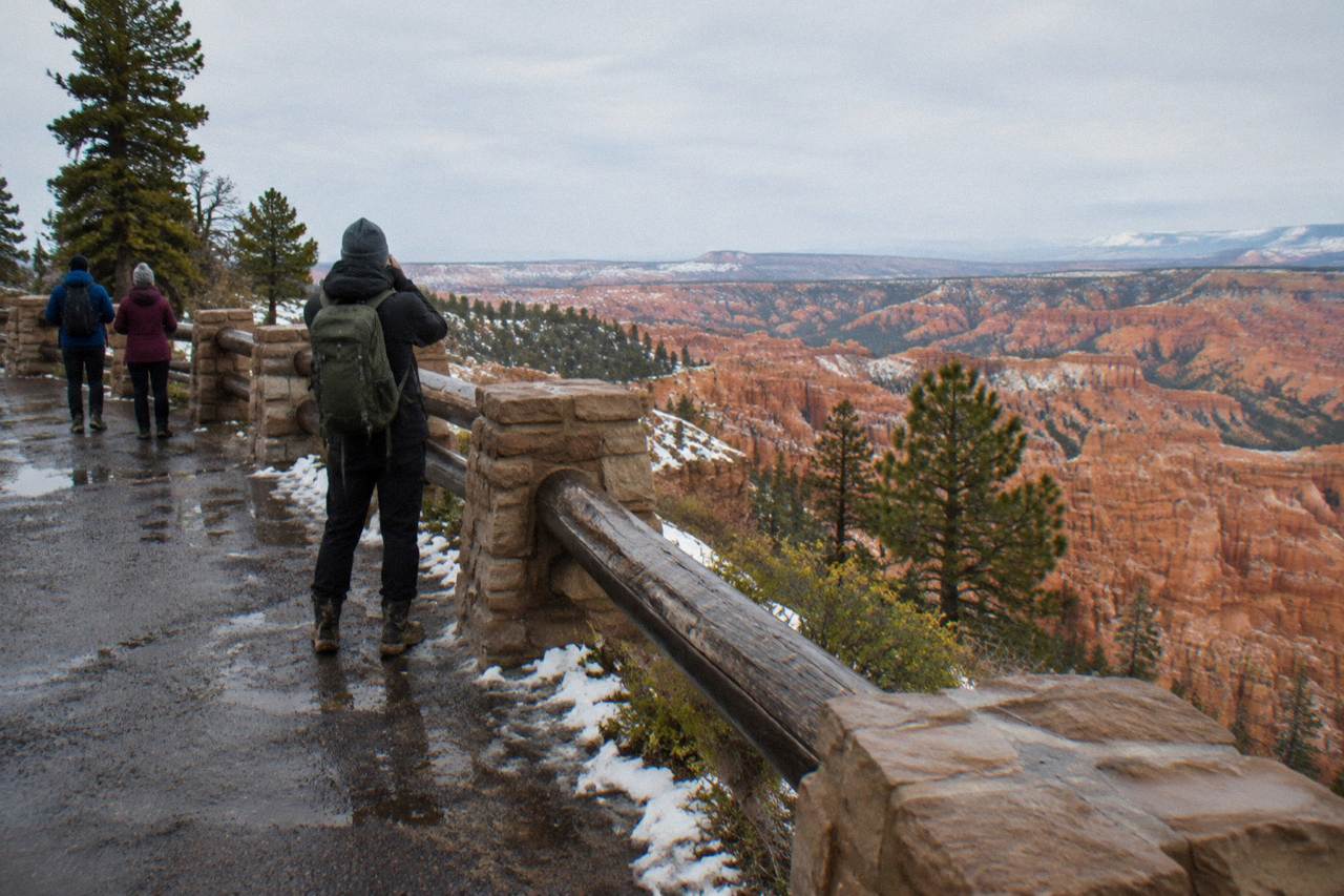 Red rock hoodoos of the Bryce Amphitheater under a pale late morning sky with patches of snow along the rim