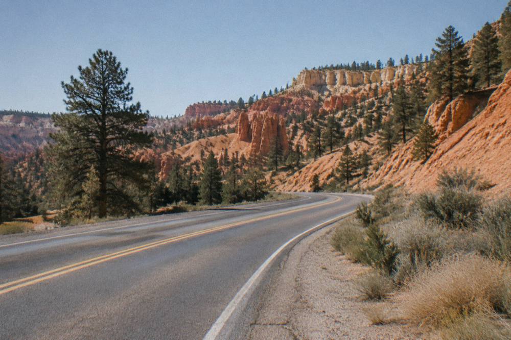 Two lane highway curving through open red rock desert with no other cars
