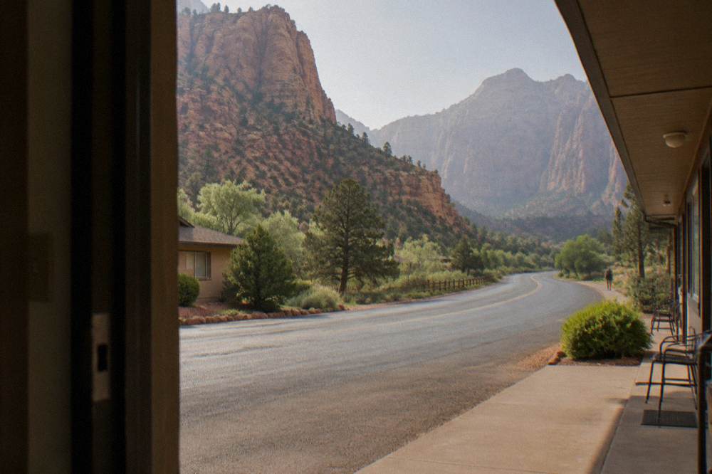 A scenic highway curving between tall red rock cliffs dotted with pine trees