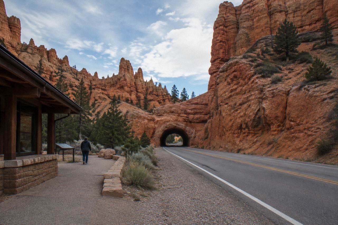 Red rock cliffs and a winding two-lane highway under a wide desert sky in southern Utah