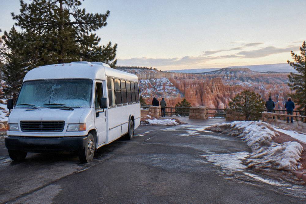 A shuttle bus stopped at a Bryce Canyon overlook parking area in morning light