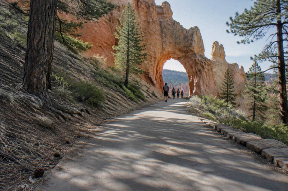 A paved path along the rim leading toward a bright sandstone arch formation