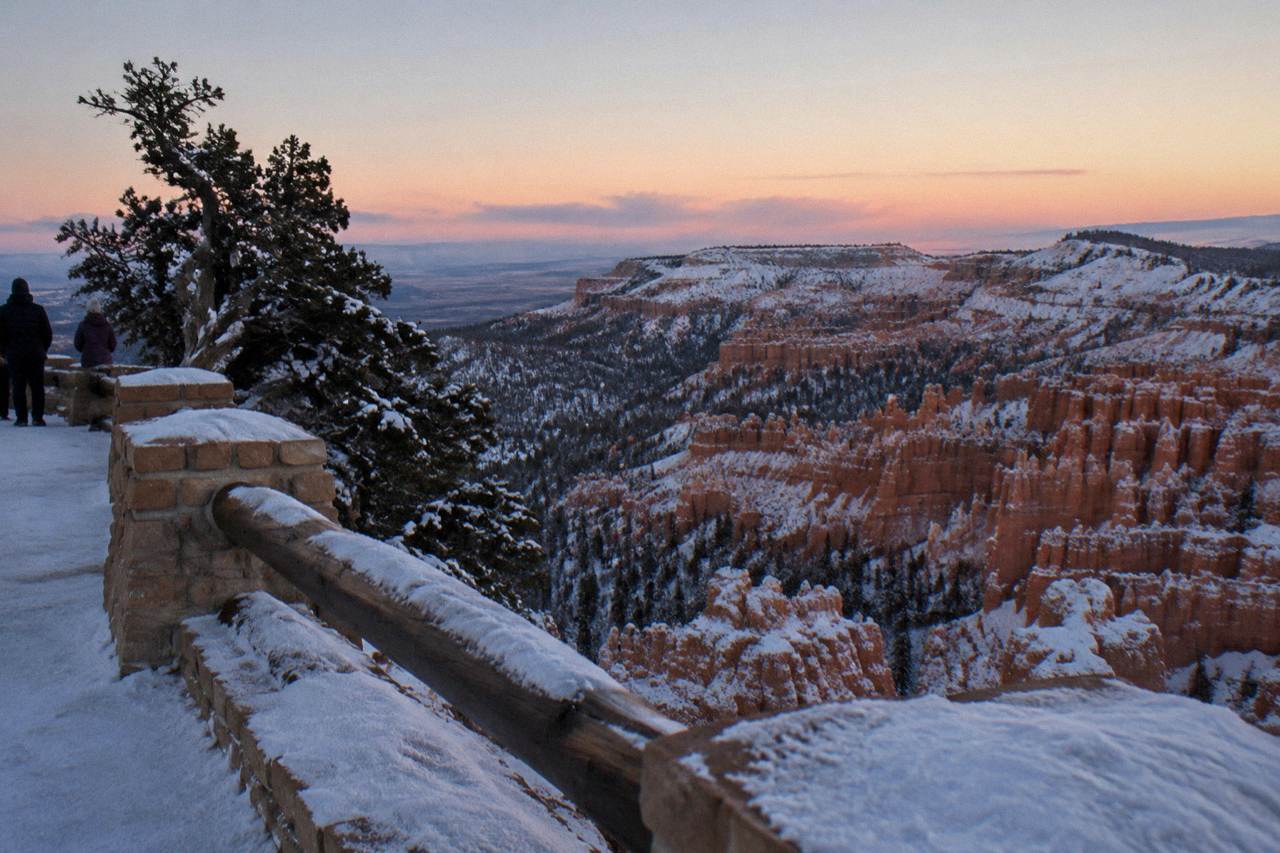 Dawn light over the eroded hoodoo amphitheater at Bryce Canyon seen from a snow-dusted overlook