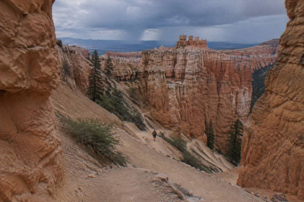 A switchback trail winding down among tall orange hoodoo spires in the Bryce Amphitheater