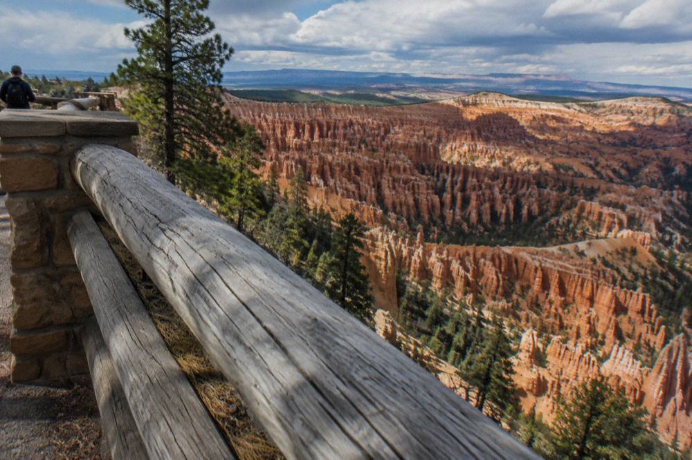 Wooden railing at a rim overlook above dense orange hoodoo spires in the Bryce Amphitheater