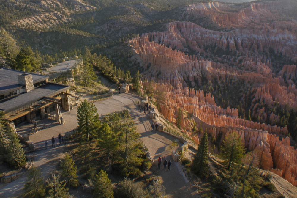 Aerial view across dense hoodoo formations and forested plateau under late afternoon light