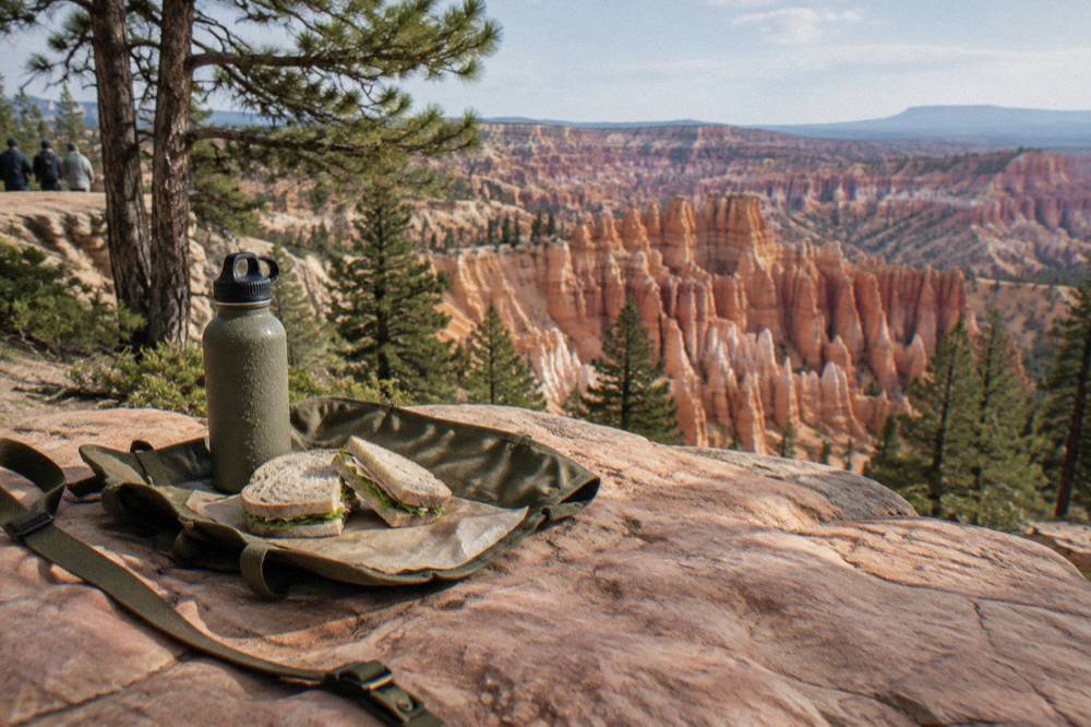 A packed picnic lunch open on a rock ledge above layered red hoodoo formations
