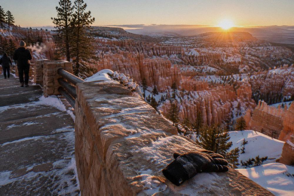 Sunrise light across a snow-dusted hoodoo amphitheater seen from a canyon rim overlook
