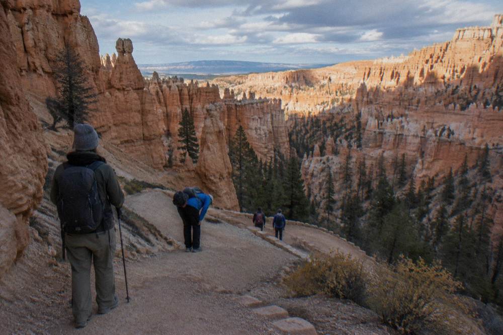 Small group of hikers with a guide on a stone trail among hoodoo walls