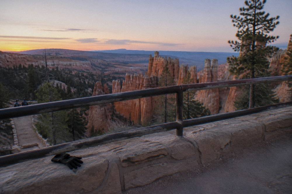 Sunrise light striking hoodoo columns below an overlook railing
