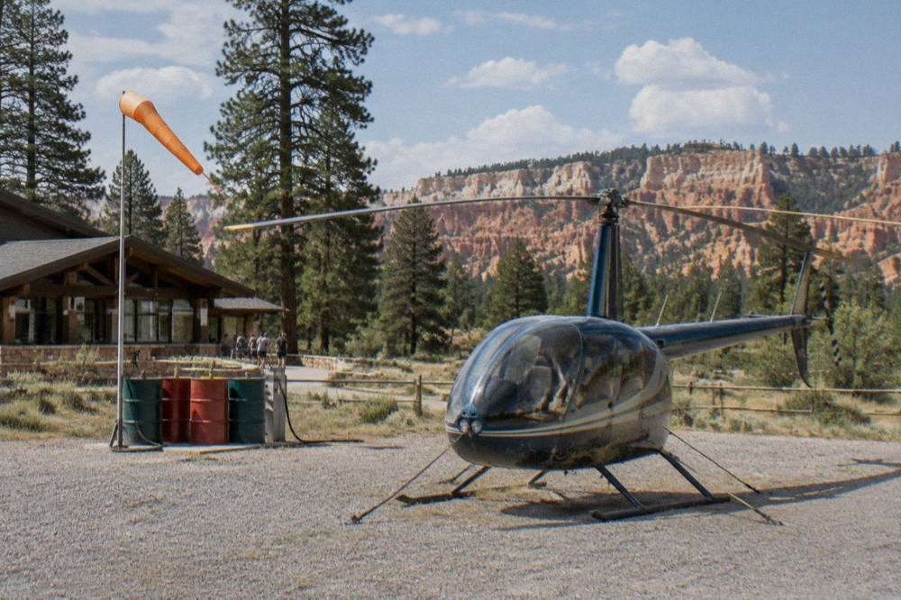 Small helicopter parked on a gravel apron at a high desert airport