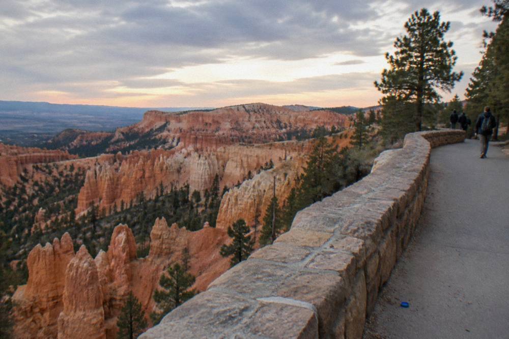 A paved rim trail curving along the edge of a canyon filled with rock pinnacles