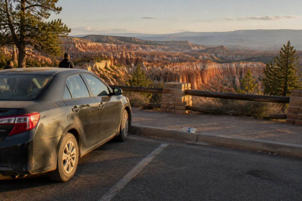 A car parked at an empty overlook along the Bryce Canyon scenic drive in late afternoon light