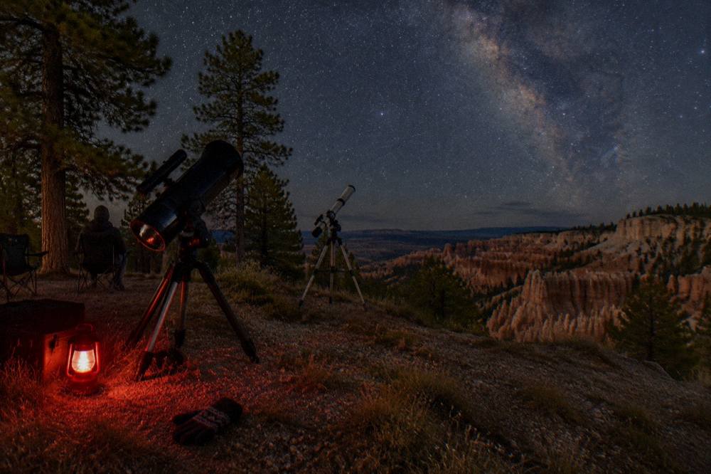 Telescope silhouetted against a star-filled sky near canyon country