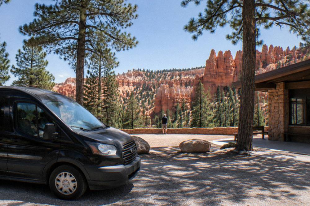 A luxury passenger van parked at a desert overlook near red rock cliffs in southern Utah