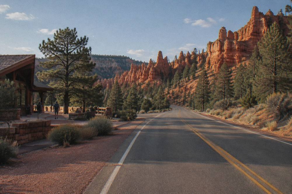 Empty desert highway stretching toward red rock cliffs in southern Utah