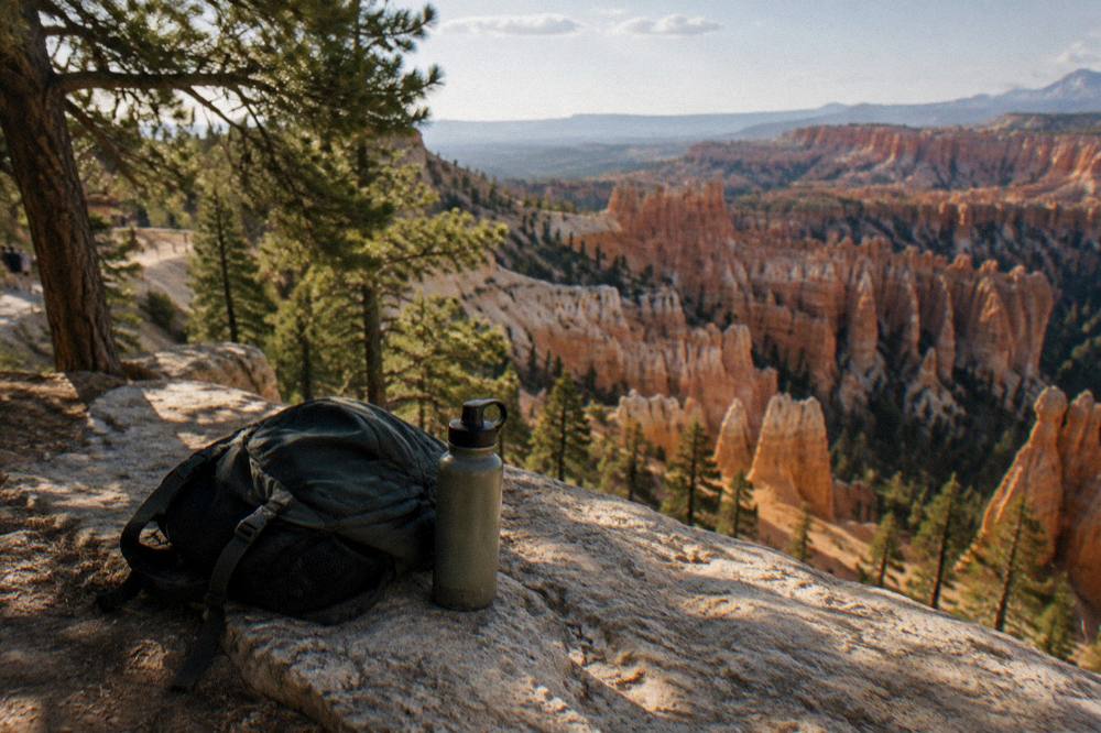 Daypack and water bottle resting on a rock ledge above a canyon