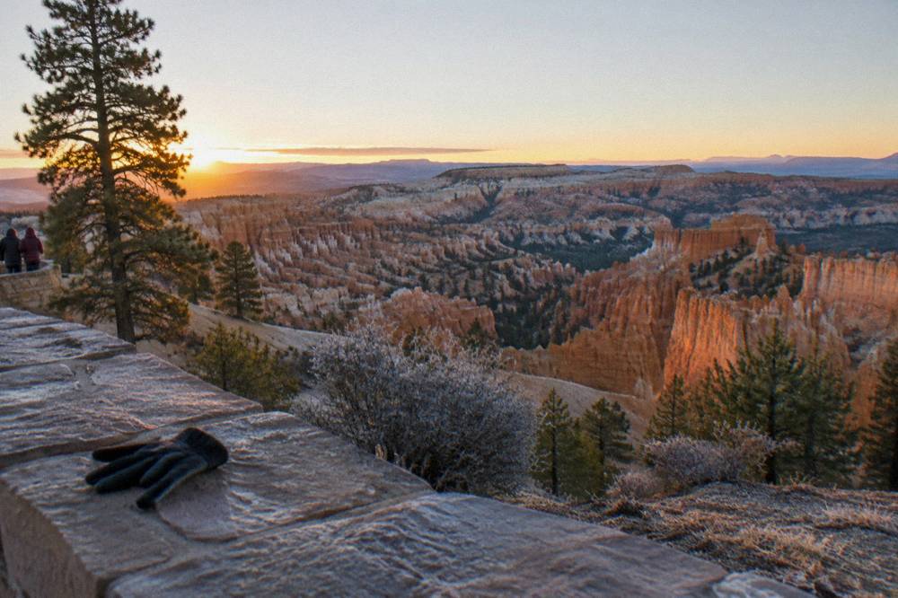 Hoodoos of the Bryce Amphitheater glowing orange at sunrise beneath a pale sky