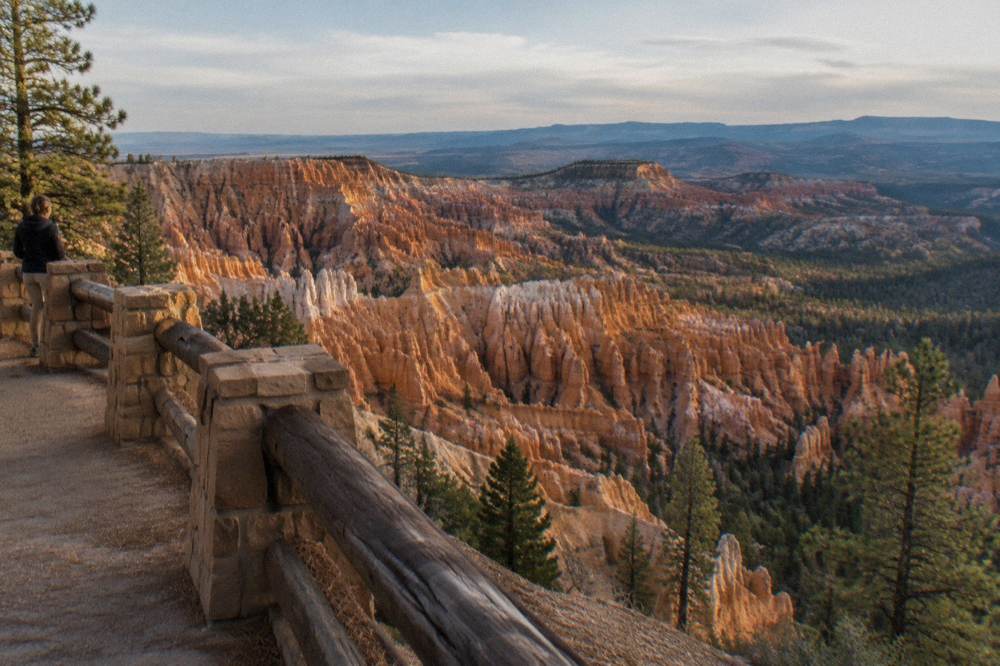 A layered panorama of stone spires and cliffs stretching toward a forested plateau