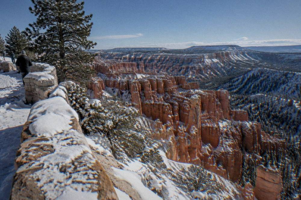 Snow-dusted hoodoos under a clear winter sky seen from the rim
