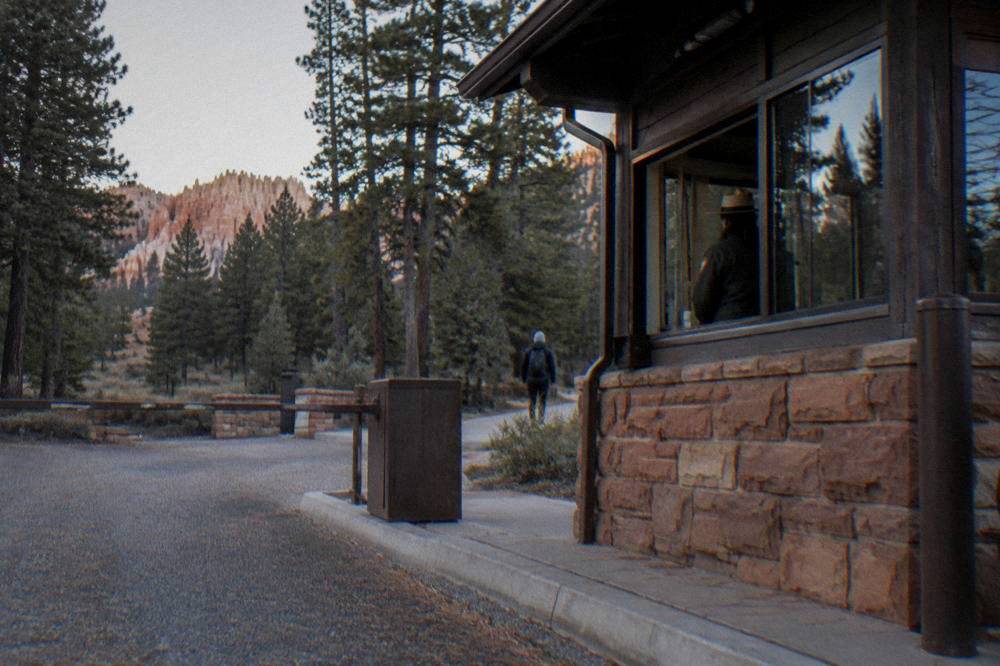 An entrance station kiosk at a national park fee booth with pine forest behind