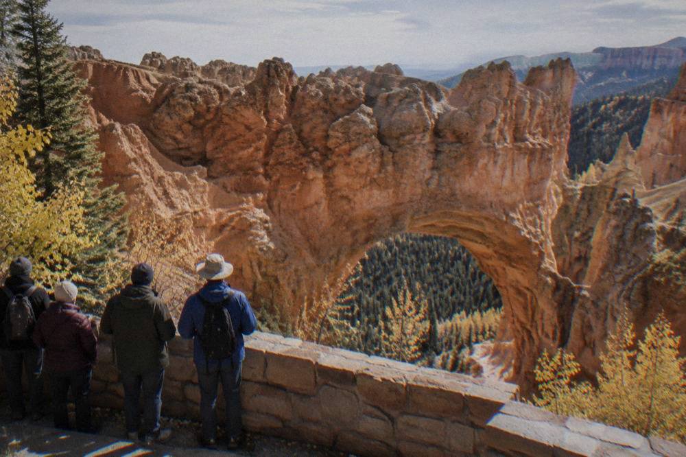 Guided tour group standing at a rim overlook above rows of orange hoodoos