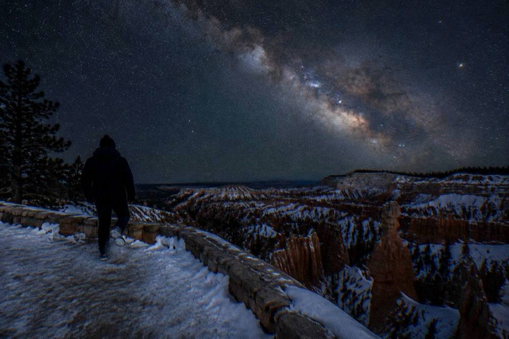Milky Way visible above silhouetted hoodoo formations at night